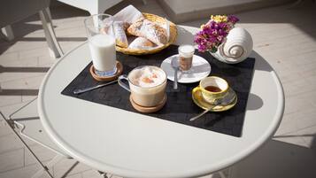 Desayuno con una mesa, leche, pasteles, café y una concha decorativa.