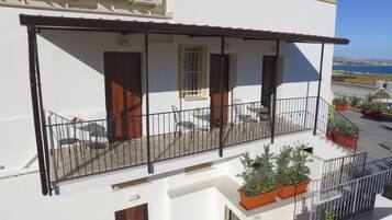 A balcony with outdoor furniture, potted plants, and air conditioning units.