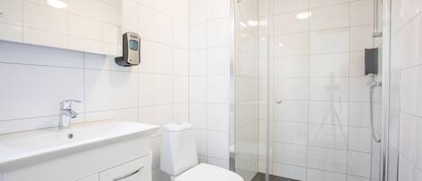 Une salle de bain moderne avec un lavabo, des toilettes et une douche, le tout de couleur blanche.
