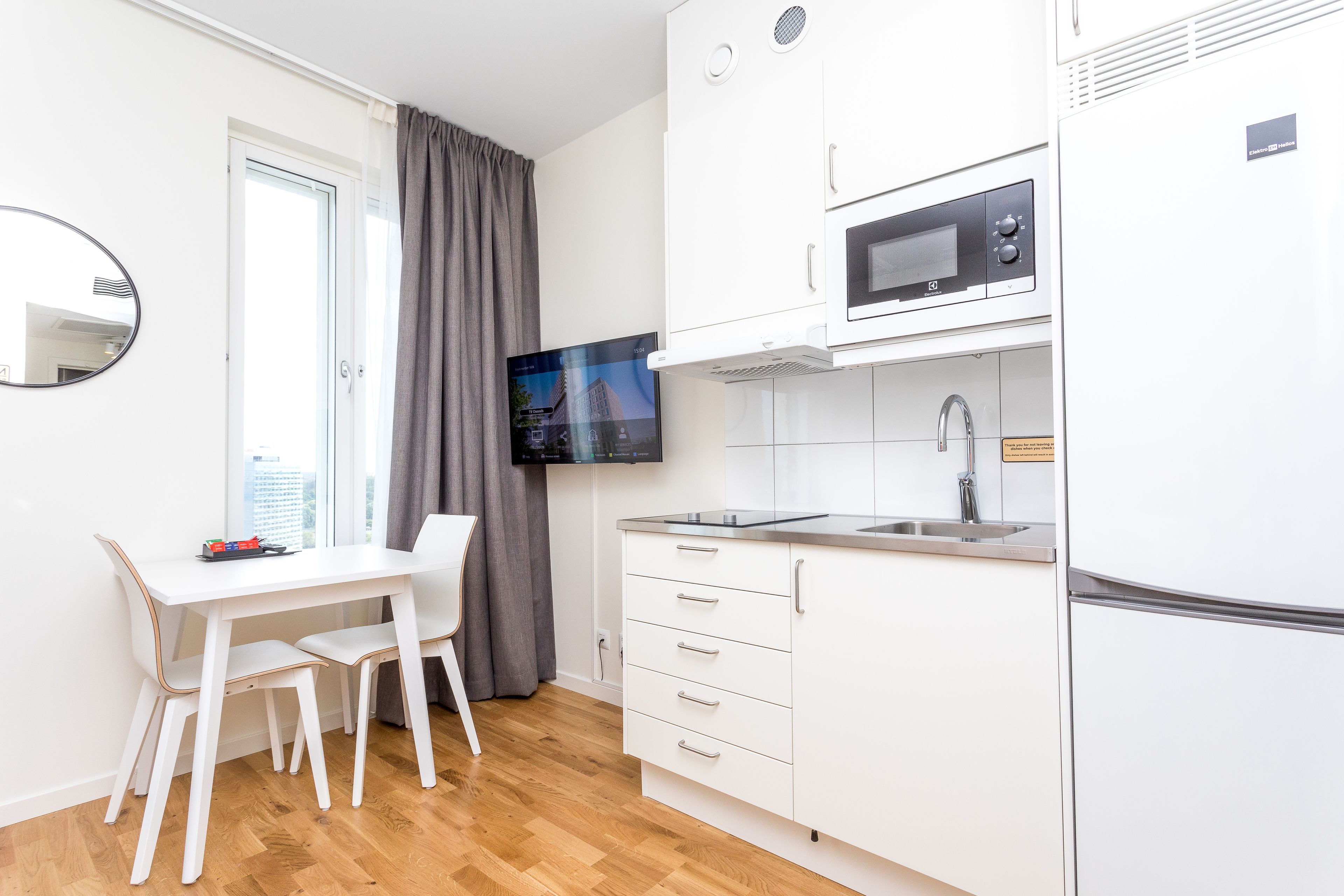 A modern kitchen with white cabinets, a built-in microwave, and a sink.