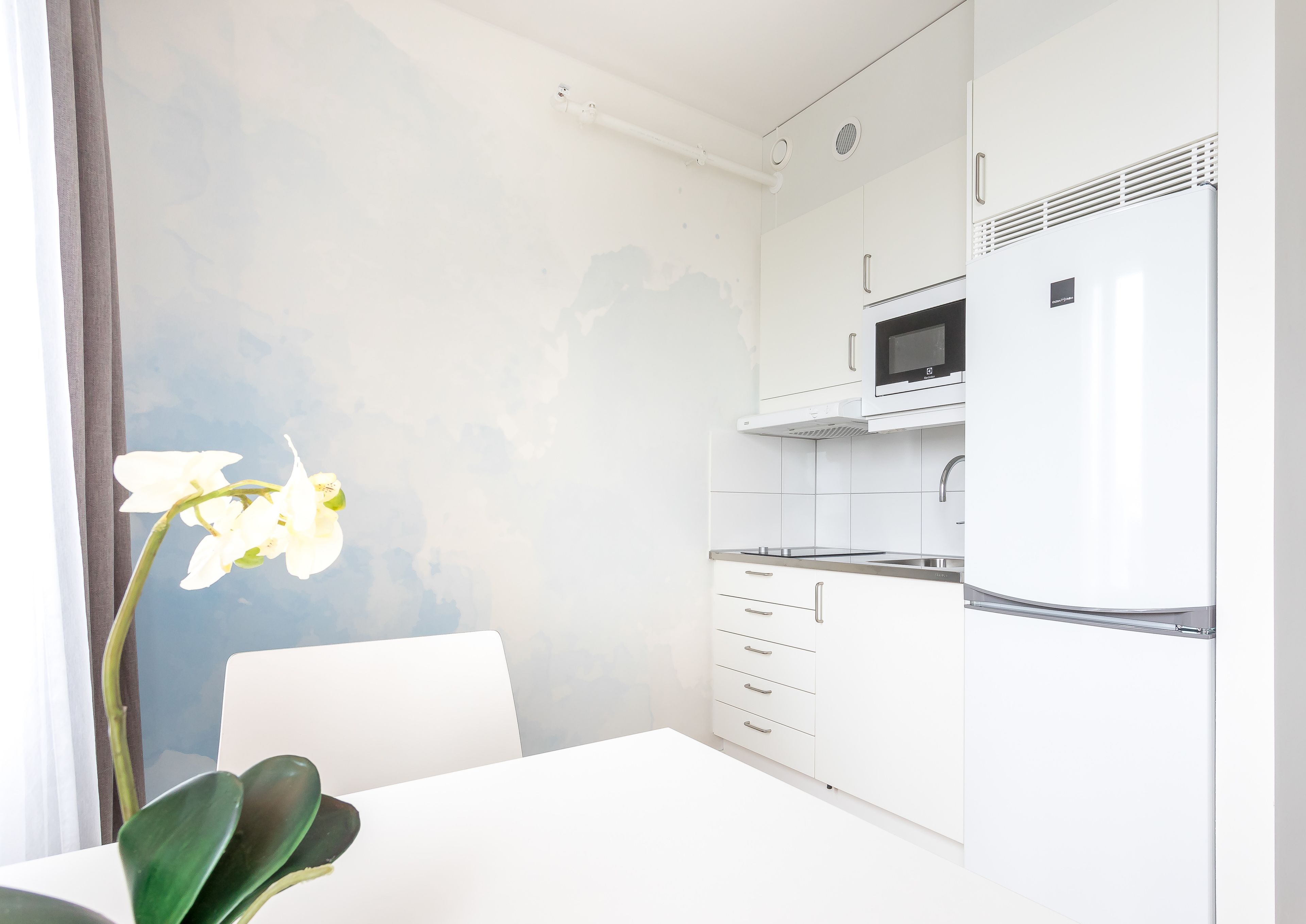 A modern kitchen with white cabinets, a built-in microwave, and a stainless steel sink.