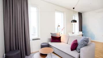 A modern living room with a grey sofa, round wooden coffee table, and a grey ottoman.