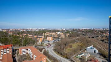 Un immeuble de grande hauteur, doté de nombreux étages, d’un parking et d’une voie ferrée qui longe le bâtiment.