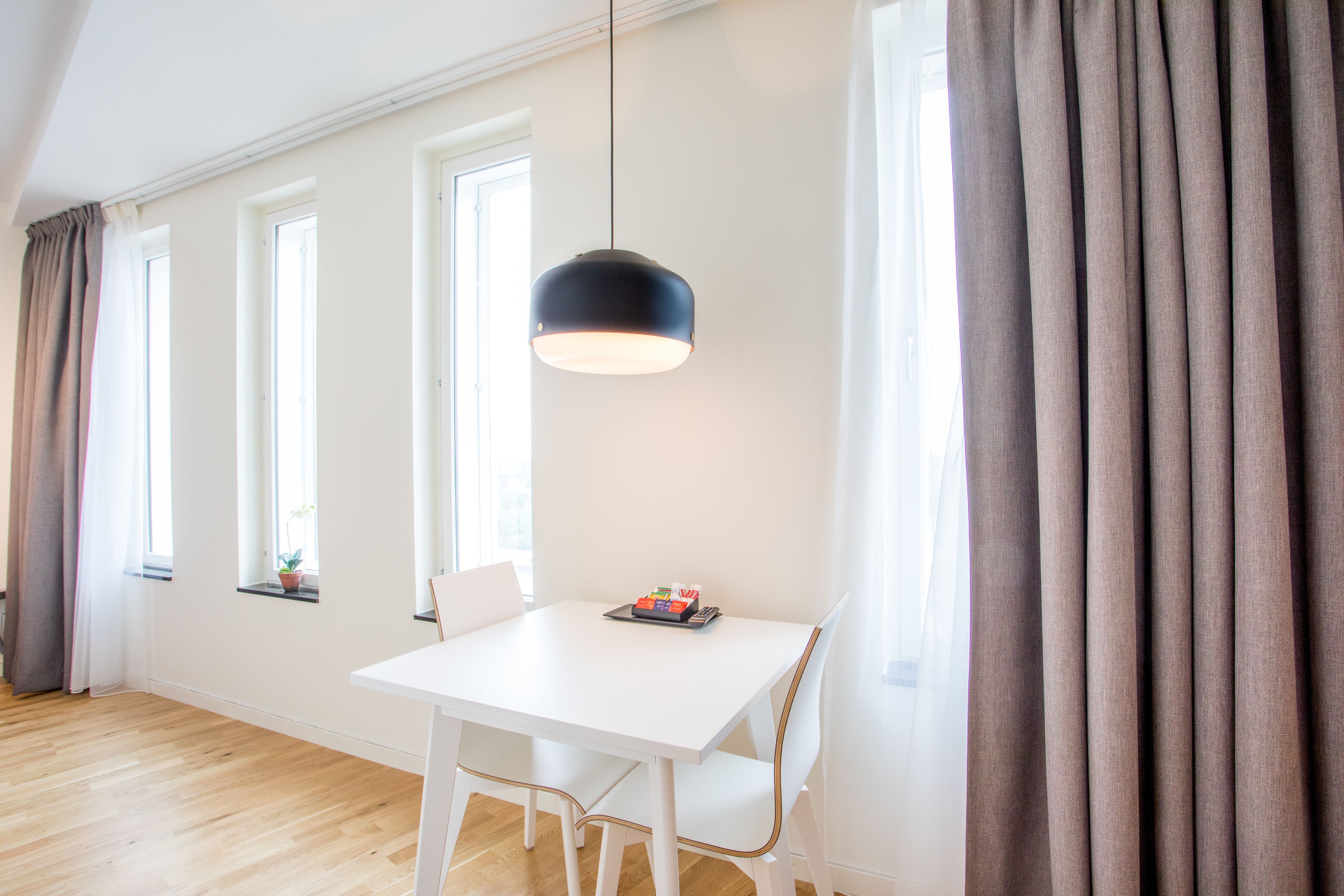 A bright room with a white table, a hanging light, and large windows.