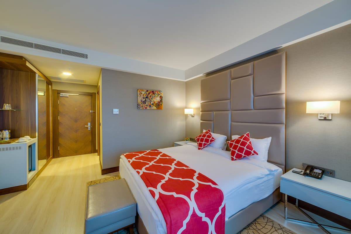 Una habitación de hotel con una cama grande, mesitas de noche, un escritorio y un baño.