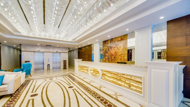 A hotel lobby with a reception desk, a patterned floor, and a chandelier. - Demircioğlu Park Hotel (Mugla)