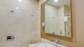 Un baño moderno con un espejo grande, un lavamanos y un inodoro.