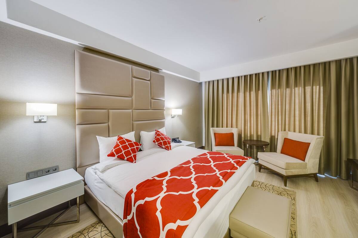 Una habitación de hotel con cama, mesita de noche, silla y una pequeña mesa.