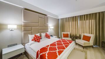 A hotel room with a bed, bedside table, chair, and a small table.