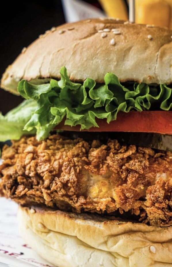 A sandwich with a bun, lettuce, and fried chicken.