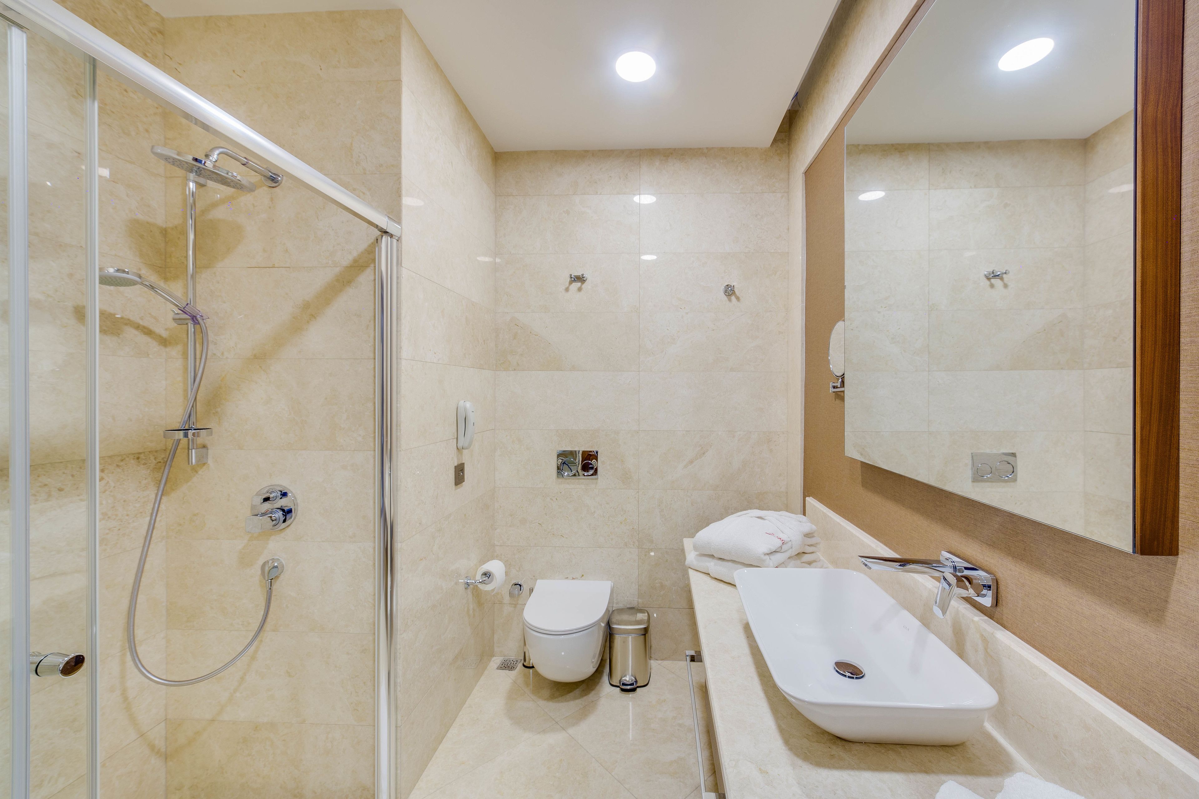 Un baño moderno con ducha acristalada, inodoro blanco, bidé y bañera independiente.