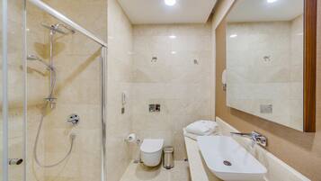 Un baño moderno con ducha acristalada, inodoro blanco, bidé y bañera independiente.