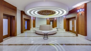 A modern hotel lobby with a central seating area, a circular light fixture, and a polished marble floor. - Demircioğlu Park Hotel (Mugla)