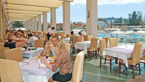 A rooftop dining area with tables and chairs, a pool in the background, and a clear sky. - Miarosa Konaklı Garden - All Inclusive (Alanya)