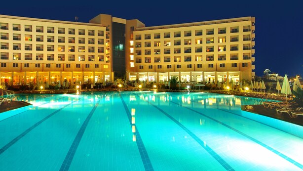 A hotel with a large swimming pool, multiple balconies, and a water slide. - Miarosa Konaklı Garden - All Inclusive (Alanya)