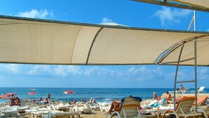 A beach with sun umbrellas, lounge chairs, and the ocean in the background. - Miarosa Konaklı Garden - All Inclusive (Alanya)