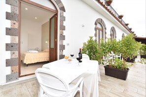 A room with a bed, a table with a bottle of wine, and a potted plant. - Terrazza Iride (Massa Lubrense)