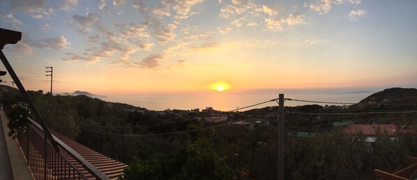 A sunset view from a balcony overlooking a residential area with houses and hills. - Terrazza Iride (Massa Lubrense)