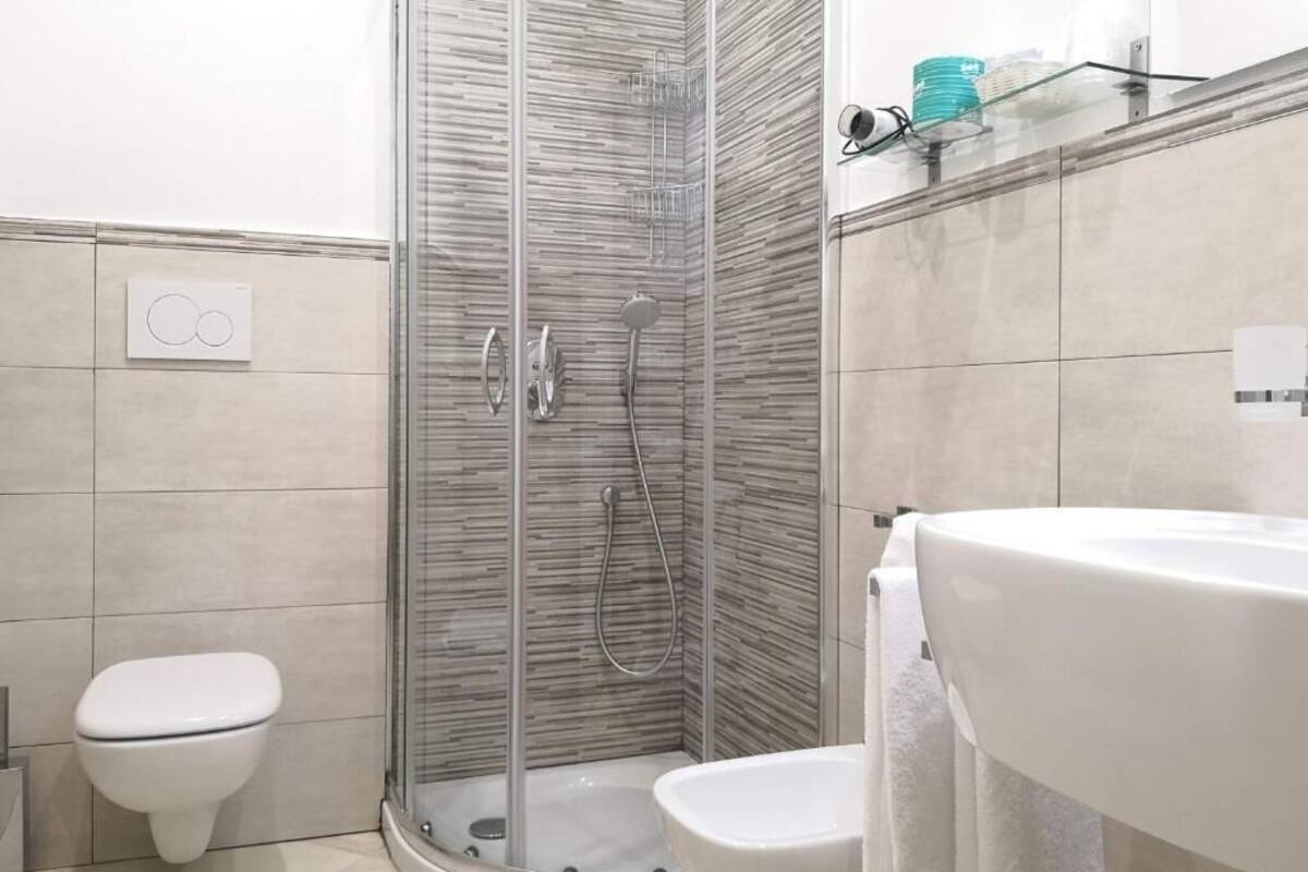 Un baño moderno con ducha de vidrio, inodoro blanco y lavamanos con toalla.