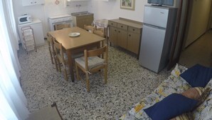 Ett kompakt kök med ett matbord, stolar, ett kylskåp, en mikrovågsugn och ett handfat.