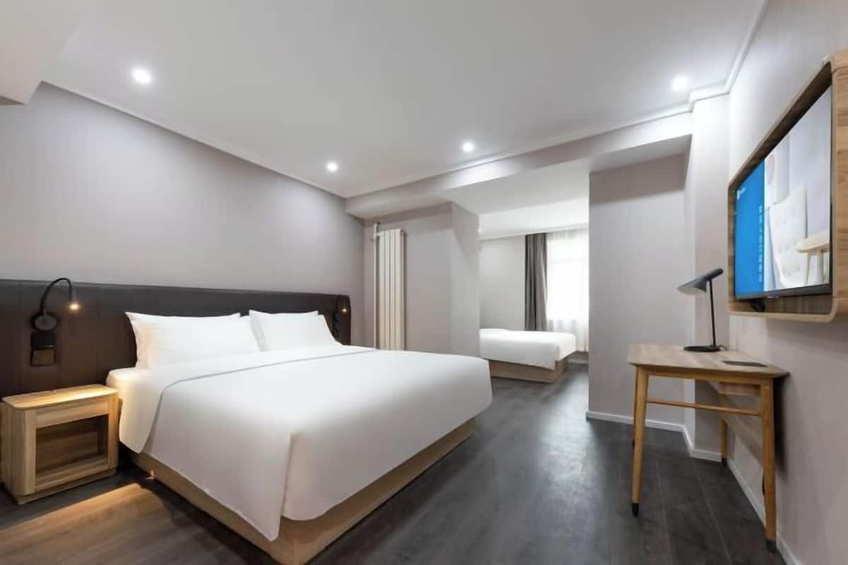 Une chambre d’hôtel moderne, dotée d’un grand lit, de tables de chevet, d’un bureau et d’une télévision.
