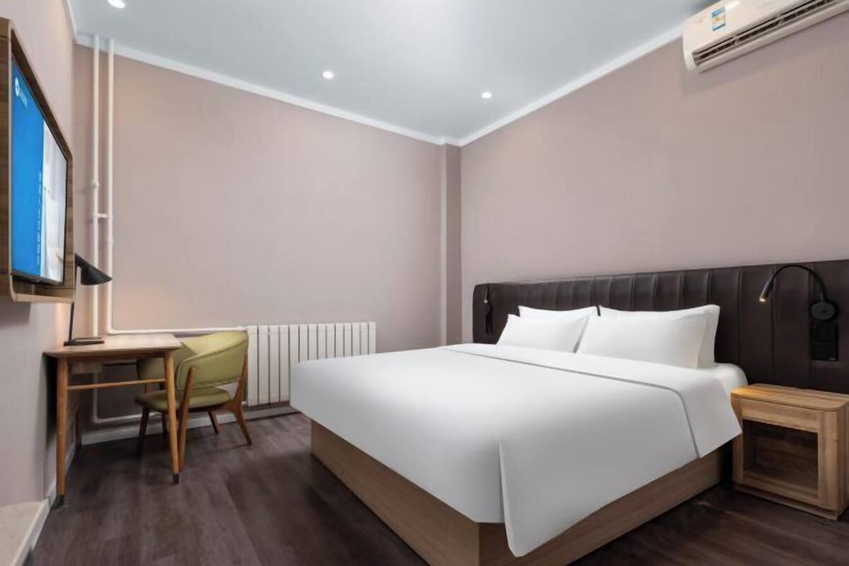 Une chambre d’hôtel moderne avec un grand lit, un bureau, une chaise et une petite table de chevet.