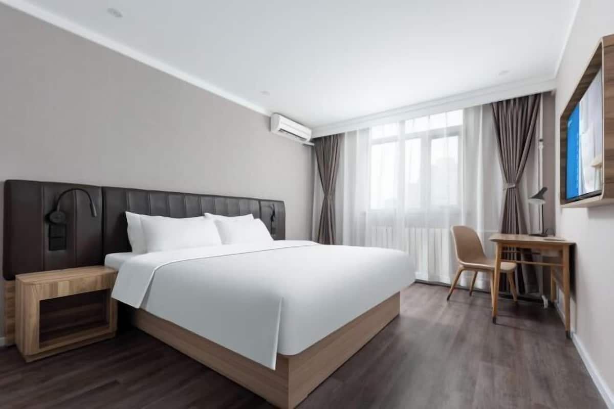 Une chambre d’hôtel moderne, dotée d’un grand lit, d’un bureau et d’une chaise.