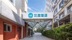 A hotel entrance with a clear sign, a covered walkway, and a hedge along the side. - HanTing Hotel (Beijing Changhong Bridge Tuanjiehu Subway Station) (Beijing)