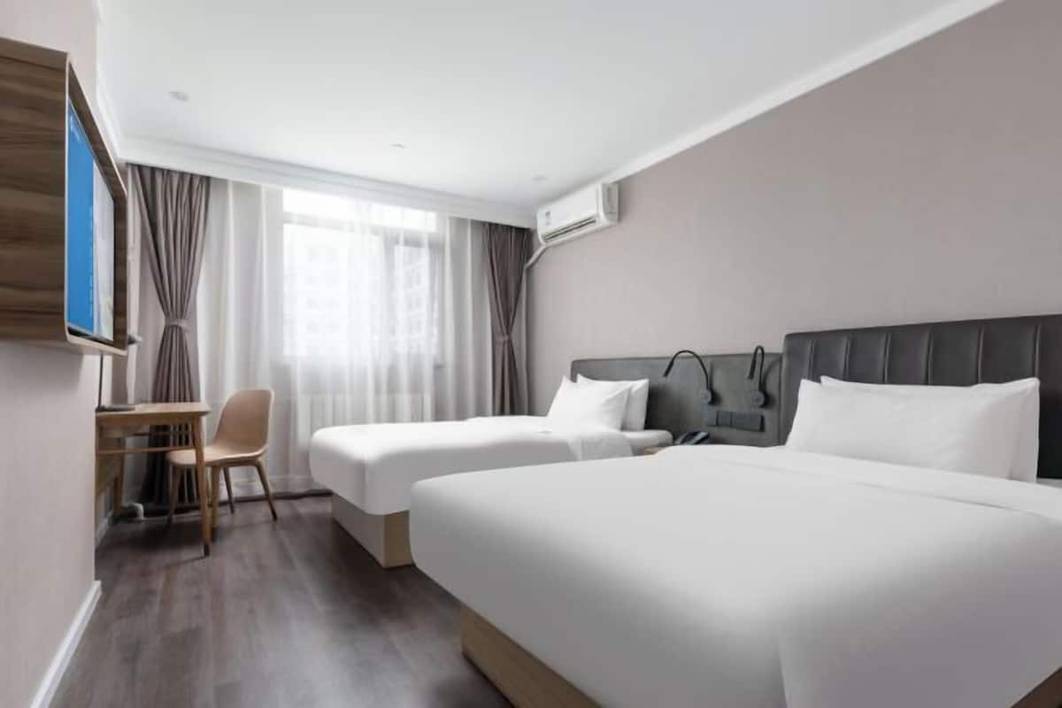 Une chambre d’hôtel avec deux lits, un bureau, une chaise et un téléviseur.