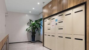 A hallway with lockers, a potted plant, and a wooden panel wall. - HanTing Hotel (Beijing Changhong Bridge Tuanjiehu Subway Station) (Beijing)