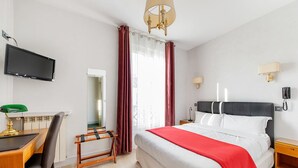 A hotel room with a bed, desk, chair, TV, and a view of the outdoors. - Crystal Hotel (Levallois-Perret)