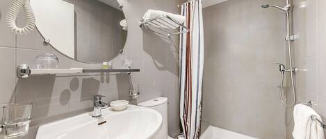 A modern bathroom with a sink, mirror, towel rack, shower, and bathtub.