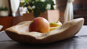 A wooden bowl containing a peach and an apple on a table. - Hotel Jägerhof (Ratingen)