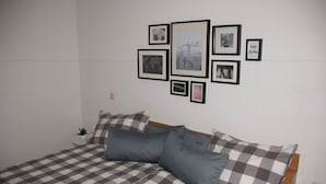 A neatly made bed with a checkered bedspread, a headboard, and several pillows. There are framed pictures on the wall above the bed, including one with the text "wonderful" and another with the text "AIRPORT". - Hotel Jägerhof (Ratingen)
