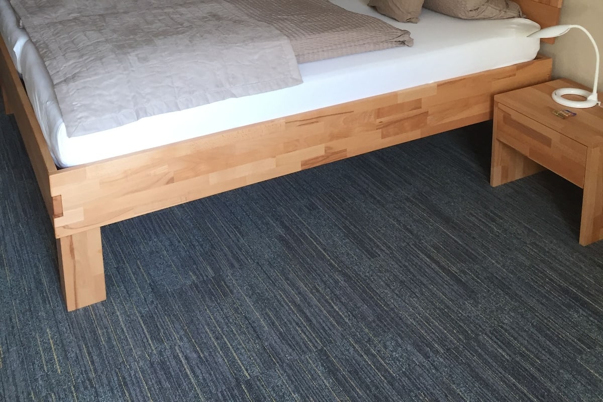 Une chambre à coucher avec un lit en bois, un bureau, une chaise, une lampe et un luminaire suspendu.