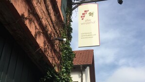 A narrow street with buildings on either side, one with a sign for a Gastehaus, Gewölbekeller, and Kochschule. - Alter Winzerhof Weisenheim am Berg e.K. (Weisenheim am Berg)