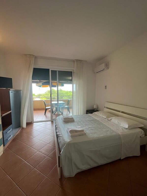 A hotel room with a bed, a desk, a chair, and a view of the outdoors.