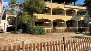 A multi-story building with balconies, outdoor umbrellas, and a wooden fence. - Jonio Vacanze Residence (Castellaneta)