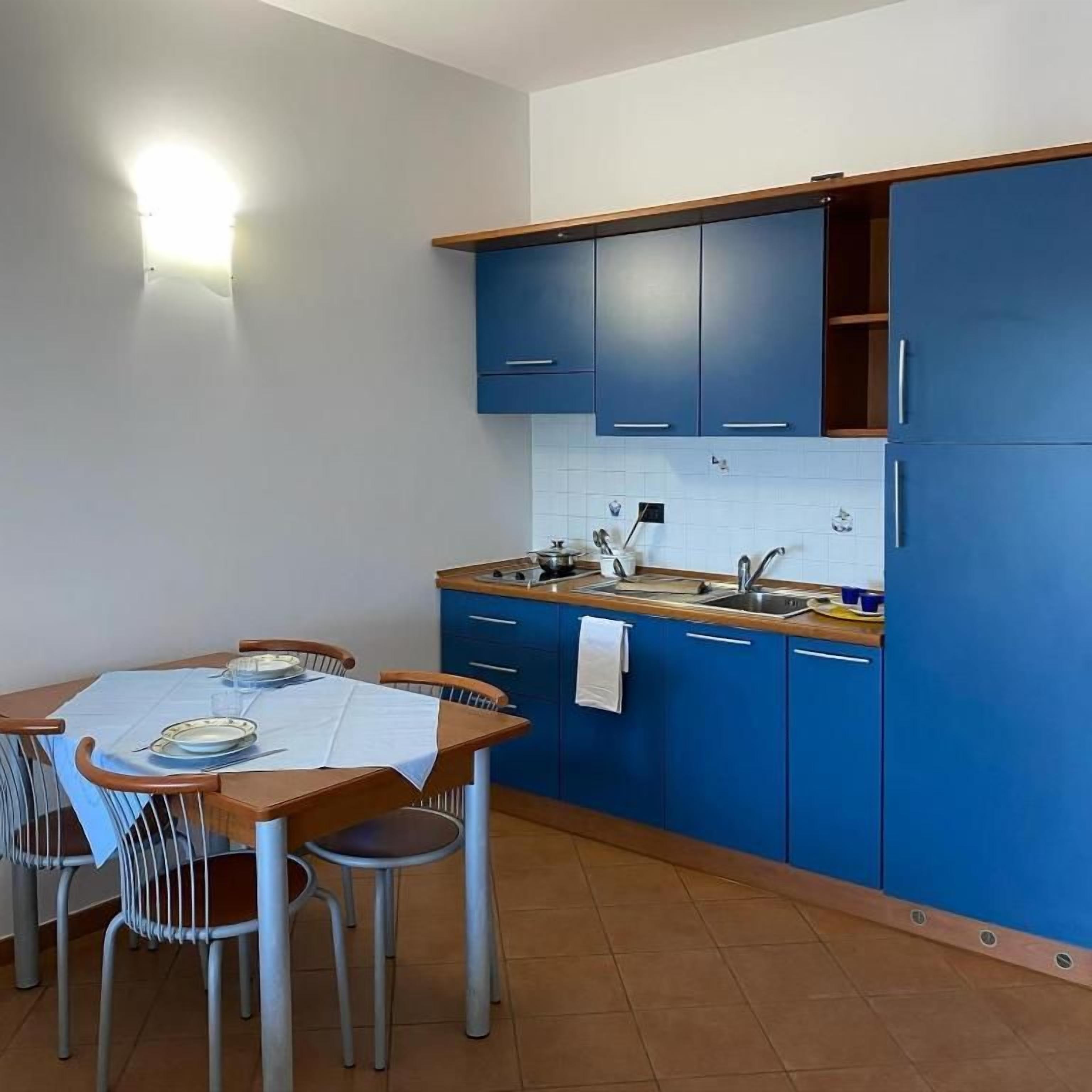 A kitchen with blue cabinets, a wooden countertop, and a dining table with chairs.