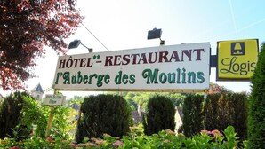 Een bord voor een hotel en restaurant genaamd 'Hôtel - Restaurant l'Auberge des Moulins' met het logo van 'Logis'.