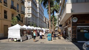 A street with white tents, palm trees, and shops. - Fan Rooms Duquesa (Málaga)