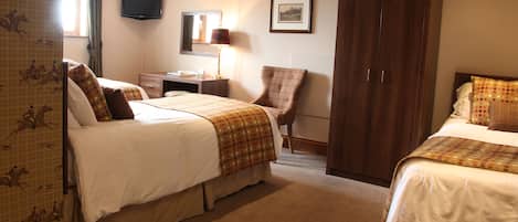 A hotel room with two beds, a desk, a chair, a wardrobe, and a television.