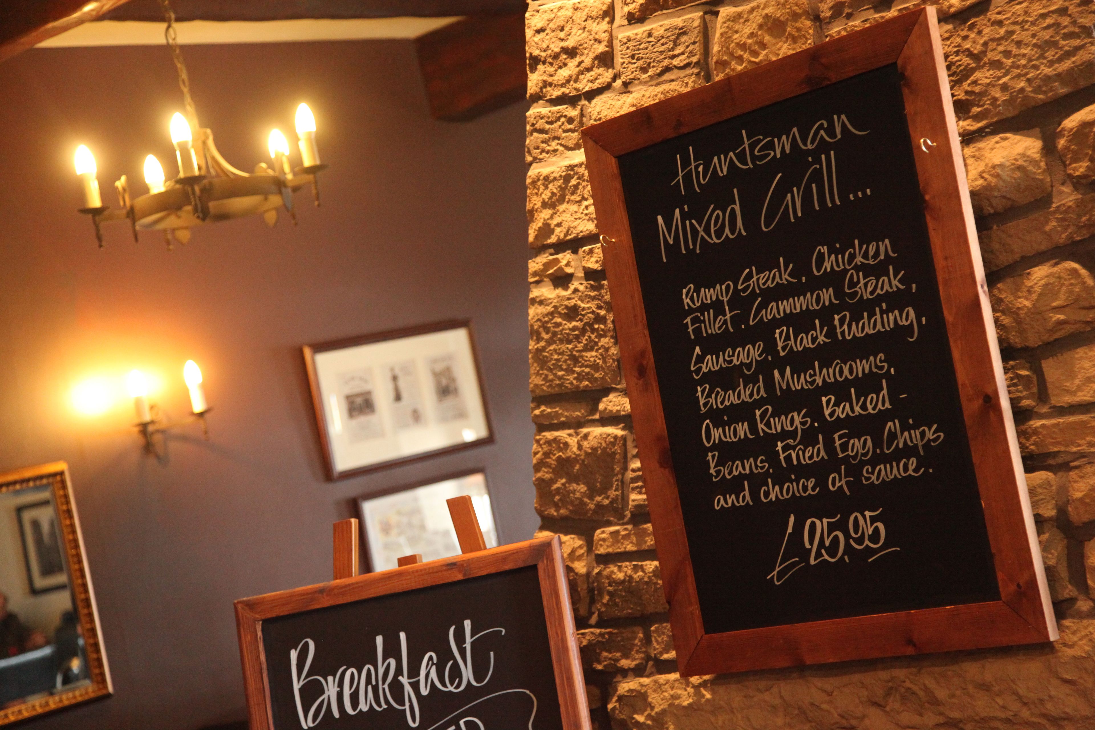 Interior de un restaurante con una pizarra que muestra un menú de varios platos y sus precios.