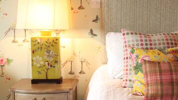 A bedroom with a nightstand, a lamp, a bed with a floral pillow, and wall decorations including birds and butterflies.