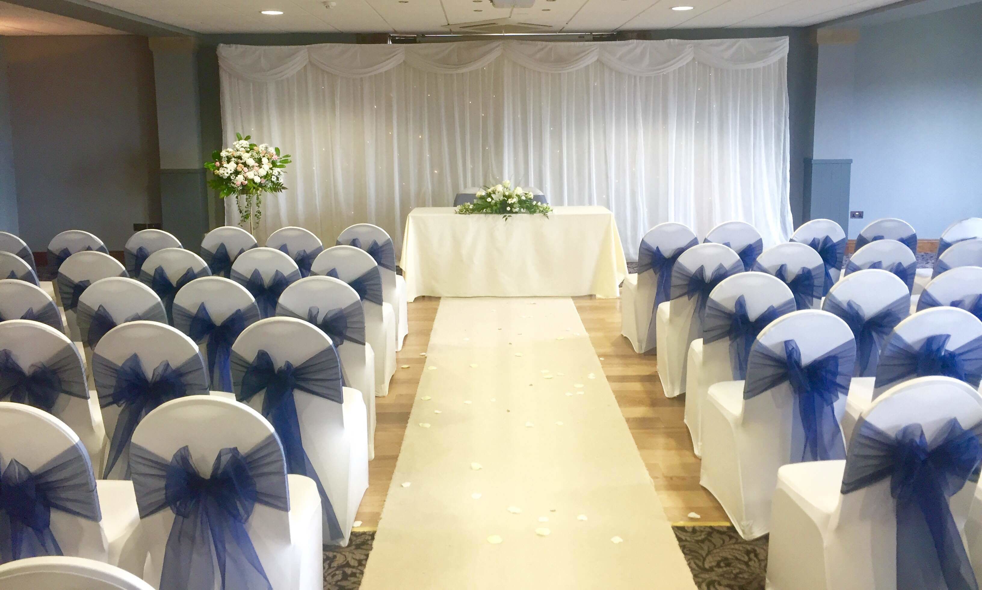 A wedding ceremony setup with rows of chairs and a white aisle.