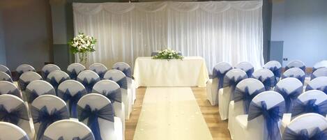 A wedding ceremony setup with rows of chairs and a white aisle.