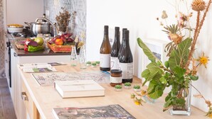 A kitchen counter with wine bottles, books, and small plants. - Etnella enoagriturismo Notti Stellate (Mascali)