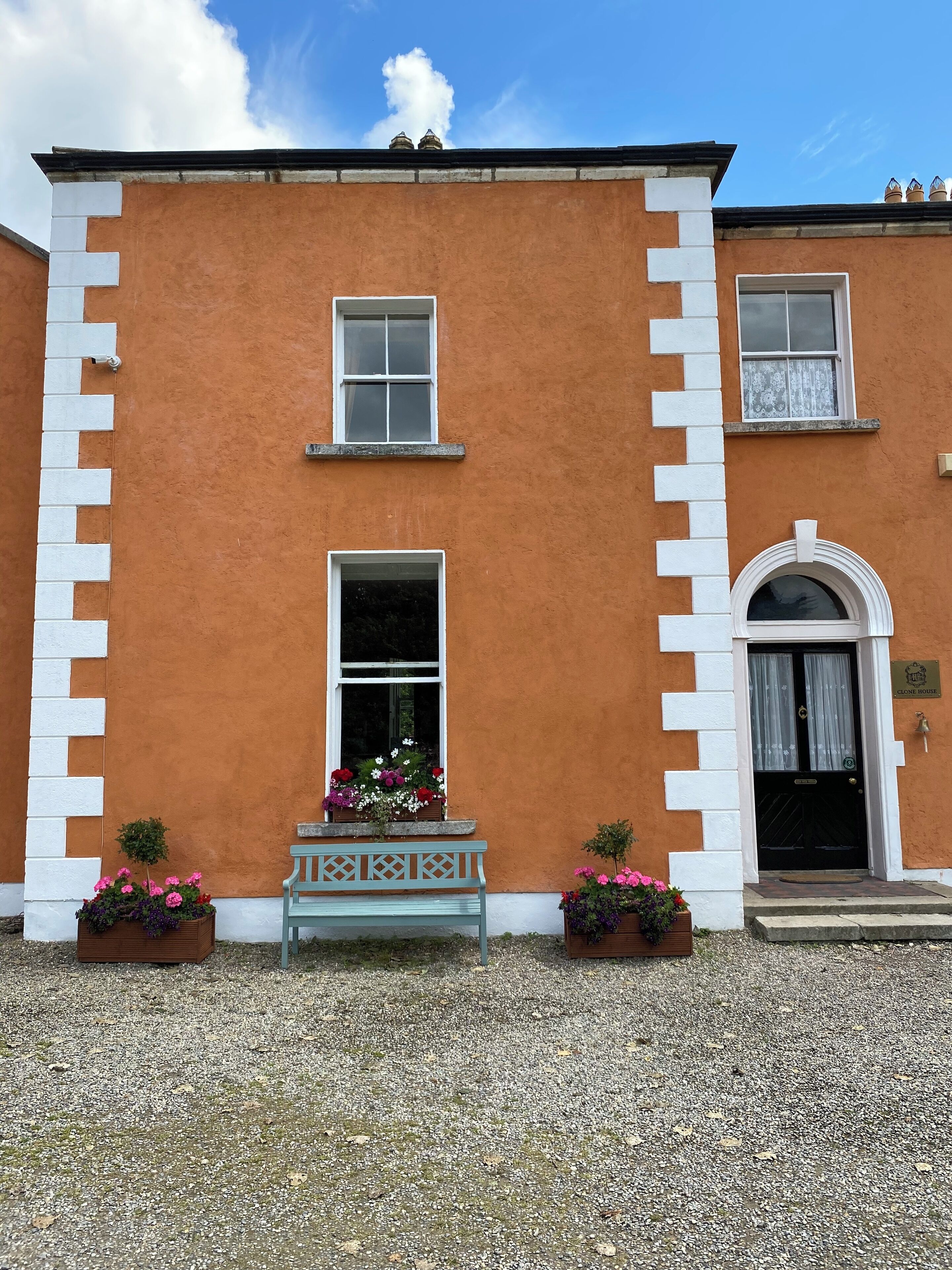 A building with a symmetrical facade, featuring a central window, a door with a small porch, and two flower boxes.