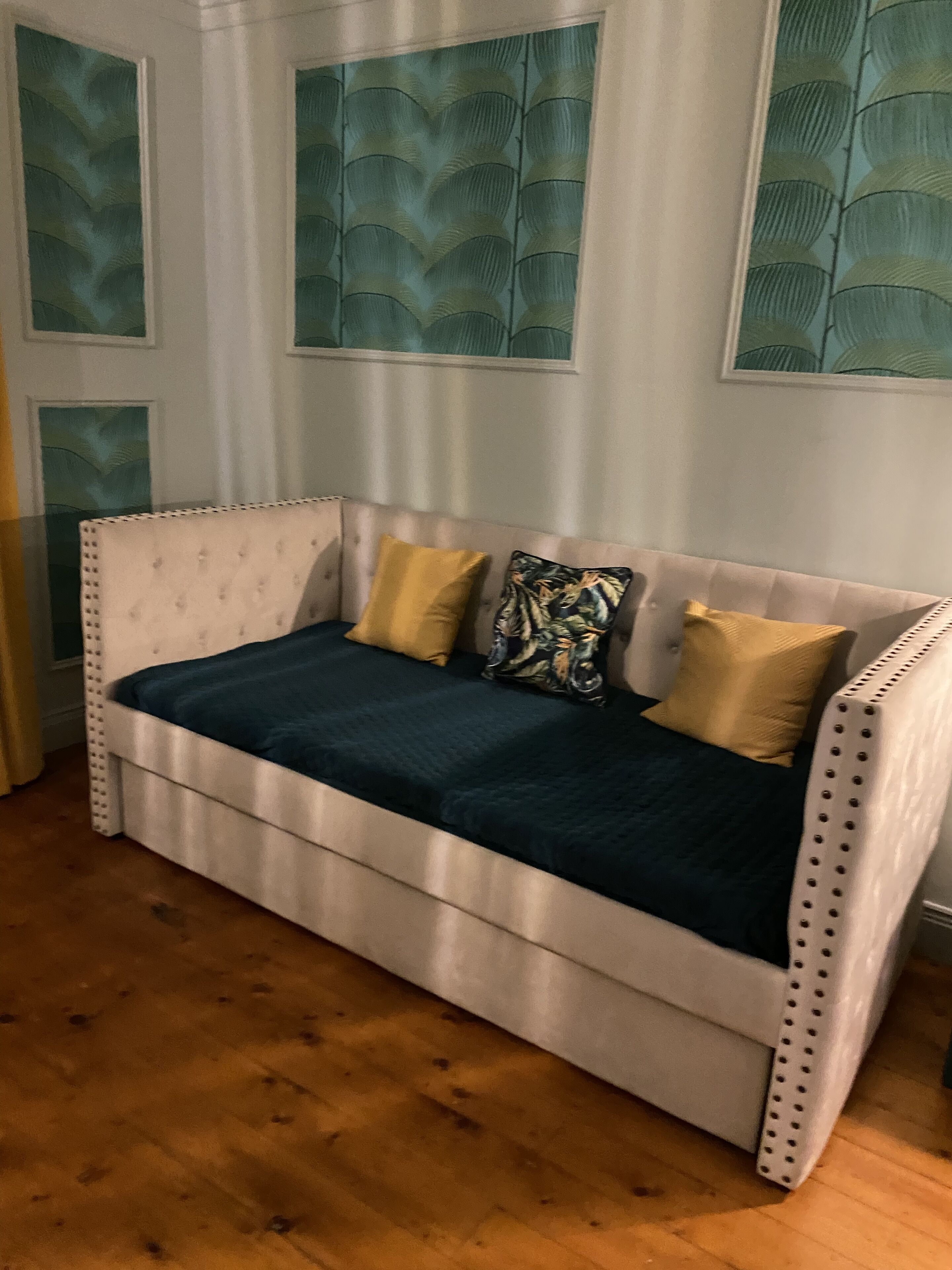 A white sofa with a dark green cover, two yellow pillows, and a patterned pillow.