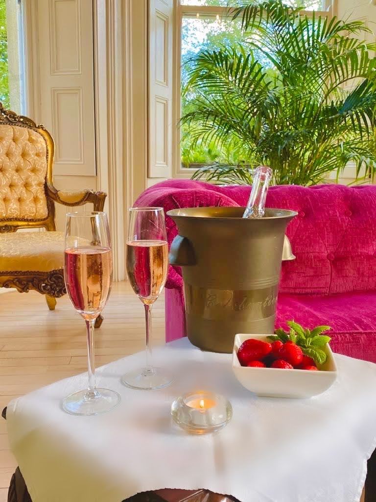 A table with two glasses of champagne, a candle, and a bowl of strawberries.